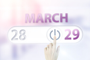 March 29th. Day 29 of month, Calendar date.Hand finger switches pointing calendar date on sunlight office background. Spring month, day of the year concept.