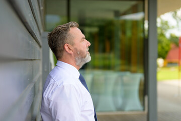 Fototapeta premium Side view portrait of a senior man standing waiting in town