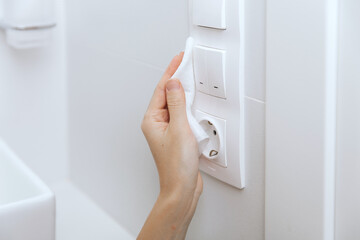 Cleaning switches and sockets with a microfiber cloth. Woman hand using wet wipe for cleaning home...