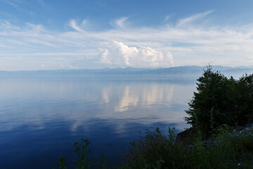 Naklejka na ściany i meble Lake Baikal in the evening. Water and beautiful white clouds. The clouds are reflected in the water.