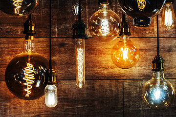 LED lamps of different shapes and sizes on the background of a wooden wall. Lighting equipment in retro style is sold in a specialized store. selective focus