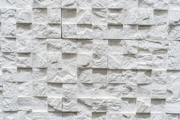 Fragment of a white wall made of decorative stone in a three-dimensional shape and square textured...