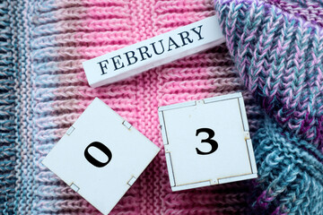 Calendar for February 3: cubes with the numbers 03, the name of the month of February in English on a multi-colored bright jersey, top view