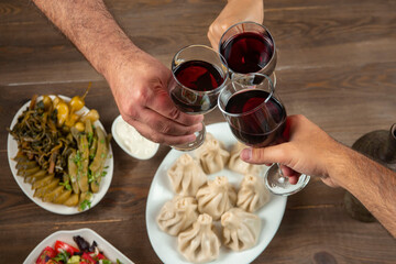 Friends drinking wine over table served with traditional Georgian dishes - , khinkali, vegetables and cheese.top view