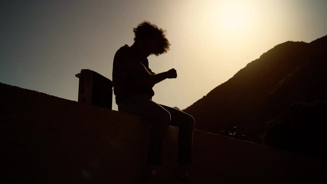 Afro man having fun dancing and listening music with vintage boombox stereo at sunset time during vacations