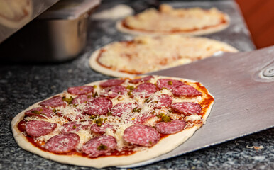 hand of chef baker making pizza at kitchen. Put on landing shovel and send it to the oven.