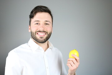 Happy caucasian man wearing white shirt is showing a lemon