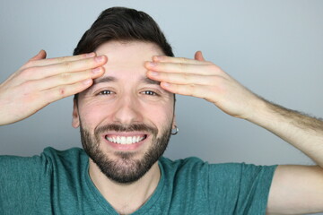 Happy young man practicing facial yoga exercise. Hands stretching forehead. 