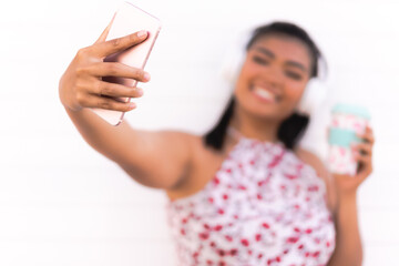 Young happy smile girl take selfie. Portrait of a woman making selfie photo on smartphone isolated on a white background. Focus on hand and smartphone.
