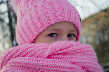 a little girl in a scarf looks at the camera