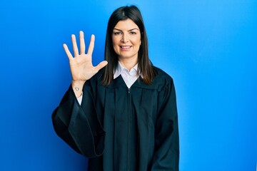 Young hispanic woman wearing judge uniform showing and pointing up with fingers number five while...
