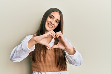 Beautiful brunette young woman wearing casual clothes smiling in love doing heart symbol shape with hands. romantic concept.