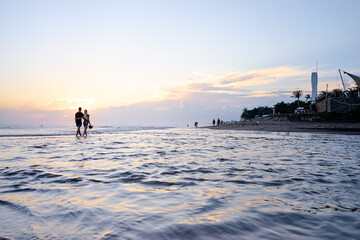 Sky and sea. Beautiful sunset. Silhouette of young loving couple walking on ocean beach.