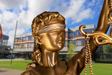 Symbolbild: Nahaufnahme einer Justitia, im Hintergrund das Bundesverfassungsgericht in Karlsruhe...