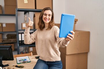 Fototapeta na wymiar Young woman working ecommerce doing video with tablet smiling happy and positive, thumb up doing excellent and approval sign