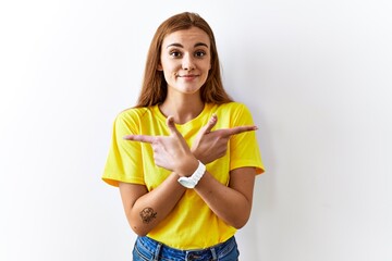 Young brunette woman standing over isolated background pointing to both sides with fingers, different direction disagree