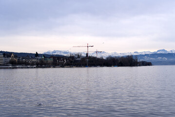 Fototapeta na wymiar Beautiful scenic landscape with Lake Zurich in the foreground and Swiss Alps in the background on a cloudy winter afternoon. Photo taken February 3rd, 2022, Zurich, Switzerland.