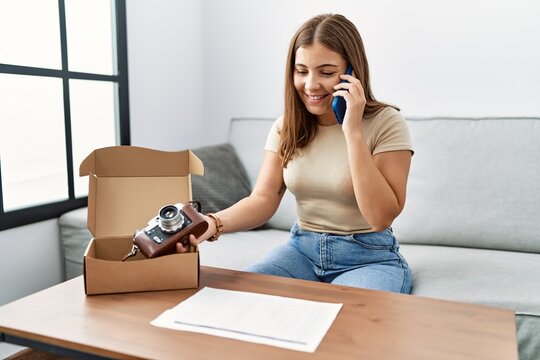Young hispanic woman talking on the smartphone reciving order at home