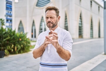 Middle age man outdoor at the city disgusted expression, displeased and fearful doing disgust face because aversion reaction. with hands raised