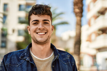 Young hispanic man smiling happy standing at the city