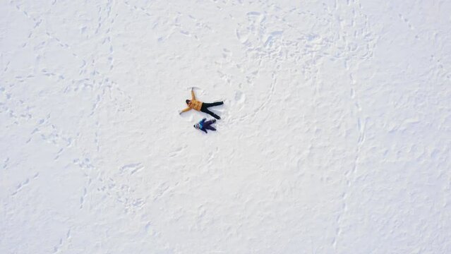 mom and baby make a snow angel. aerial photography