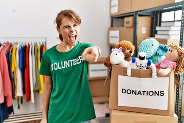 Beautiful caucasian woman wearing volunteer t shirt at donations stand pointing displeased and...