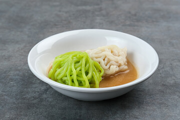 Kue Putu Mayang is traditional Indonesian snack made from rice flour strands curled up into a ball, served with coconut milk and palm sugar. Selected focus.
