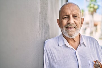 Obraz premium Senior man smiling confident leaning on wall at street