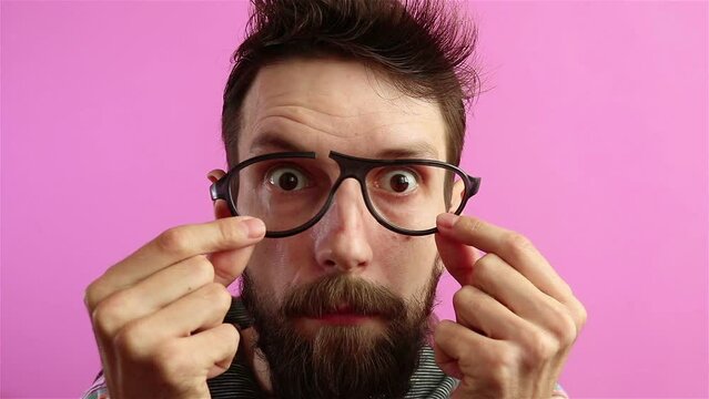 upset bearded  man using broken glasses on pink bakground 