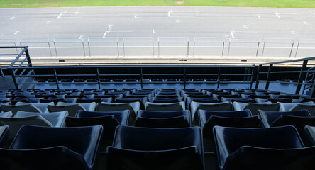 Empty seating on grandstand overlooking the racing track background.
