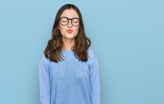Young beautiful woman wearing casual clothes and glasses looking at the camera blowing a kiss on air being lovely and sexy. love expression.