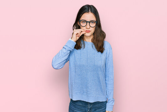 Young beautiful woman wearing casual clothes and glasses mouth and lips shut as zip with fingers. secret and silent, taboo talking