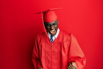 Young african american man wearing graduation cap and ceremony robe very happy and excited doing...