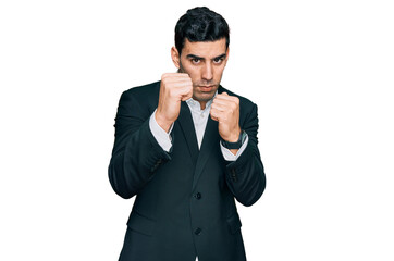 Handsome hispanic man wearing business clothes ready to fight with fist defense gesture, angry and upset face, afraid of problem