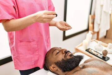 Fototapeta na wymiar Young african american man having skin facial treatment at beauty center