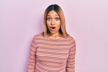 Fototapeta premium Beautiful hispanic woman wearing casual striped sweater afraid and shocked with surprise expression, fear and excited face.