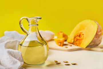 Organic pumpkin seeds oil in a glass bottle on yellow background