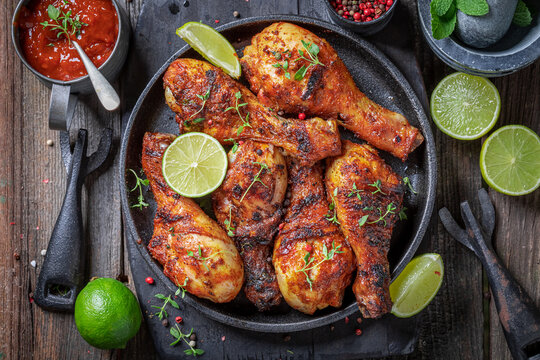 Spicy roasted chicken leg served with lime and sauces.