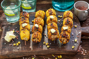 Hot grilled corn cob with melting butter on stick.