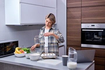 Baking Concept. Portrait Of Young Woman In Casual Outfit Mixing Dough In Bright Cozy Kitchen Interior, Short Haired Female Preparing Homemade Pastry, Enjoy Weekends, At Day Time