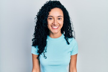 Young hispanic woman with curly hair wearing casual blue t shirt with a happy and cool smile on face. lucky person.