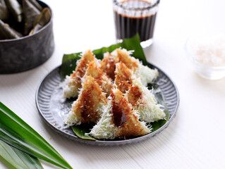 Lupis, Indonesian Traditional Snack Made From Sticky Rice, Wrapped with Banana Leaf, Shape Triangle  Served with Liquid Palm Sugar and Grated  Coconut