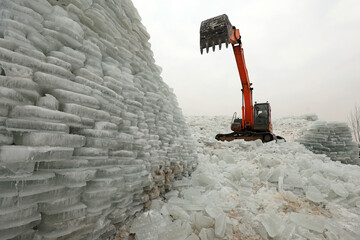 farmers use excavators to sort out ice cubes outdoors in North China
