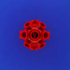 A simple element with tentacles that looks like a red coronavirus on a bright blue background to illustrate the spread and infection