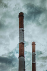 High pipes of an industrial enterprise against the background of clouds