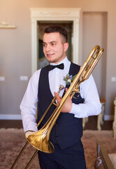 Young groom professional trumpeter holding a trumpet in his hands.