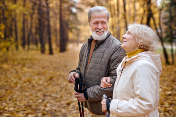 Senior couple hiking in the autumn forest. Aged caucasian Spouses on a trip in the park. Wonderful picturesque autumn scenery landscape. leisure, rest, walk, relationships, healthy lifestyle