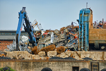 Close view of backhoe loader and big pile of construction debris in river port in overcast day....