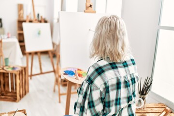 Young artist student girl on back view painting at art studio.