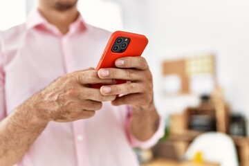 Young hispanic man using smartphone at office